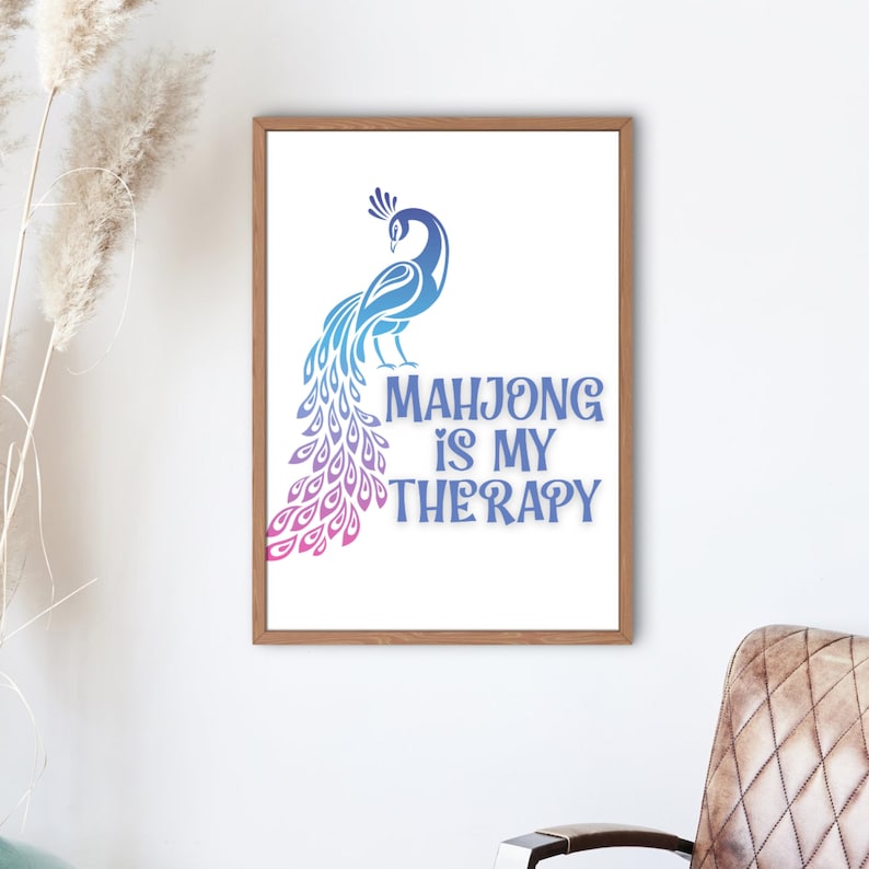 May include: A framed print with a peacock design in blue and purple hues. The text "MAHJONG IS MY THERAPY" is below the peacock illustration. The print is set against a white background, enclosed within a wooden frame.