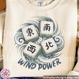 Op de afbeelding: Crèmekleurige sweatshirt met een afbeelding van vier Mahjong-tegels met Chinese karakters, omgeven door een blauw en groen golfpatroon. De woorden "WIND POWER" staan eronder in een donkerblauwe letter.