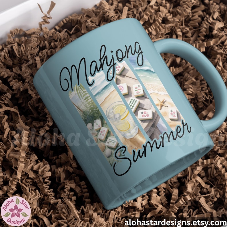 May include: A pale blue ceramic mug with the words "Mahjong Summer" in black script. The mug features a beach scene with mahjong tiles, a drink with lemon slices, and a starfish. The mug is presented in a box with brown paper filler.