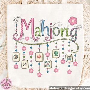 May include: Cream-colored tote bag featuring the word "Mahjong" in colorful, whimsical lettering. Below the word are hanging Mahjong tiles and pink flower accents. The bag has a simple design with a floral logo in the corner.