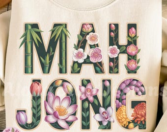Könnte beinhalten: Cremefarbenes Sweatshirt mit dem Wort "MAH JONG" in dunkelgrüner Schrift, jeder Buchstabe mit floralen und Bambus-Illustrationen verziert. Das Design umfasst rosa, weiße und gelbe Blumen. Der Text "Aloha Star Designs" ist sichtbar.