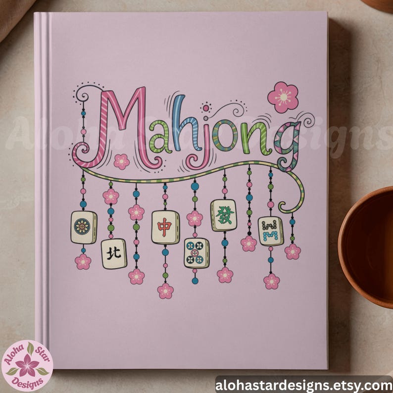 May include: A pink notebook with the word "Mahjong" in a colorful, whimsical font. The design includes hanging tiles and pink flower accents, with the text "alohastardesigns.etsy.com" at the bottom.