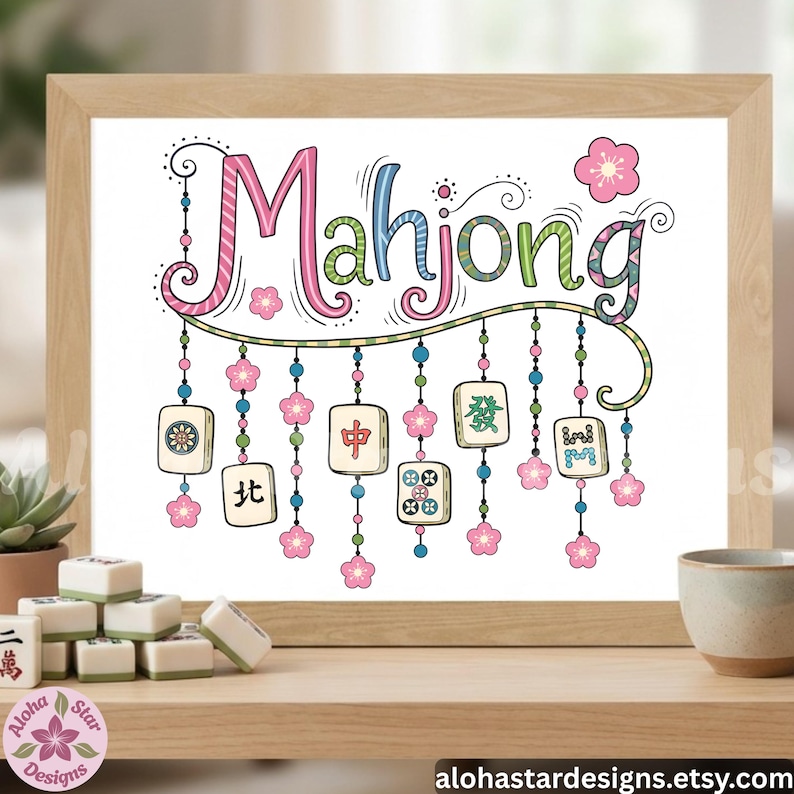 May include: A framed print with the word "Mahjong" in colorful, whimsical lettering. The design includes hanging tiles and pink flower accents. The print is displayed on a wooden shelf with Mahjong tiles and a small cup.
