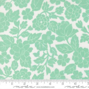 May include: A white fabric featuring a repeating floral pattern in mint green. The design consists of various flowers and leaves arranged across the surface. A ruler is visible at the bottom edge, showing measurements in inches up to 7 inches.