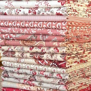 May include: A tall stack of folded fabric pieces featuring a variety of patterns including floral, paisley, and striped designs in shades of red, pink, cream, and white. The textiles are neatly layered, showcasing diverse botanical motifs.