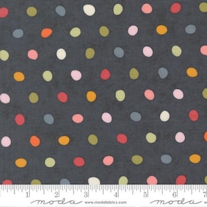 May include: Dark gray fabric with a repeating pattern of colorful polka dots. The dots are in shades of red, orange, yellow, green, pink, blue, and white. The fabric has a textured appearance and a ruler is at the bottom.