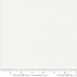 May include: Off-white fabric with a subtle dotted pattern. The dots are evenly spaced across the surface. A ruler is visible along the bottom edge, marked with inch increments. The fabric appears to be cotton or a similar material.