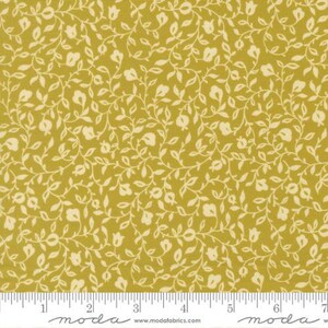 May include: A mustard yellow fabric featuring a repeating pattern of cream-colored vines, leaves, and small tulip-like flowers. The bottom edge displays a white ruler with inch markings and the text "moda" and "www.modafabrics.com".