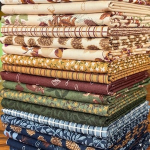 May include: A stack of various fabric pieces with floral and nature-themed patterns. The fabrics feature colors like cream, brown, green, and navy. Some fabrics have leaf, acorn, and floral designs, while others have plaid or striped patterns. The fabrics are neatly folded.