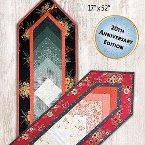 May include: A quilt pattern titled "Braid Runner" with dimensions of 17" x 52". The design features a geometric pattern with floral accents and a color palette of red, black, and white. The text "20th Anniversary Edition" is also visible.