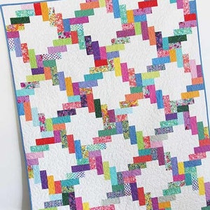 May include: A colorful quilt pattern called "Jelly Twist" with a white background and a variety of bright colors. The quilt is made with a jelly roll and is available in four sizes. The quilt is shown on a wooden floor with a white wall in the background. The text "Cluck Cluck Sew" is visible in the lower left corner of the image.