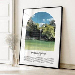 May include: Framed print featuring a scenic view of Dripping Springs, Texas, with a waterfall cascading into a turquoise pool. The image is framed by an archway, with text at the bottom that reads "Dripping Springs, Texas United States."