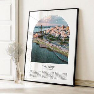 May include: A framed print featuring an aerial view of Porto Alegre, Brazil, within an arched design. The image showcases a cityscape with buildings, roads, and a river, under a sky with soft colors. The print includes the city's name and text.