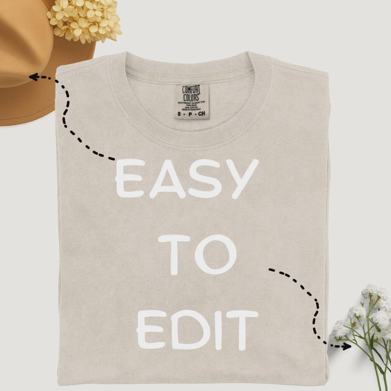 May include: A beige Comfort Colors t-shirt with the words "EASY TO EDIT" printed in white. The shirt is folded and has a crew neck. The Comfort Colors logo is visible on the upper back of the shirt.