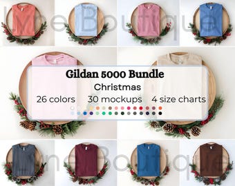 May include: A collection of t-shirt mockups in various colors, including coral, light blue, and pink, arranged on wooden platters with festive greenery. The image includes text that reads "Gildan 5000 Bundle Christmas" with 26 colors, 30 mockups, and 4 size charts.
