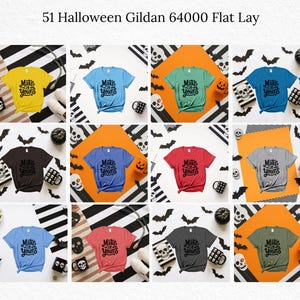 May include: A flat lay featuring a variety of Gildan 64000 t-shirts in various colors, each with the text "Make it Yours" in a black, stylized font. The shirts are arranged with Halloween-themed decorations, including bats, skulls, and pumpkins.
