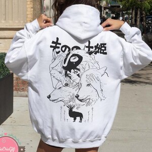 May include: White hoodie featuring a black and white graphic of a woman, wolves, and a deer. Japanese text is above the graphic. The hoodie has a drawstring hood and long sleeves.