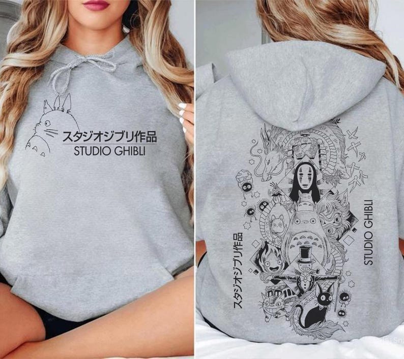 May include: A light gray hoodie featuring a black graphic of a cartoon character and Japanese text. The front of the hoodie has the text "STUDIO GHIBLI". The back of the hoodie has a larger graphic with multiple characters and the same text.