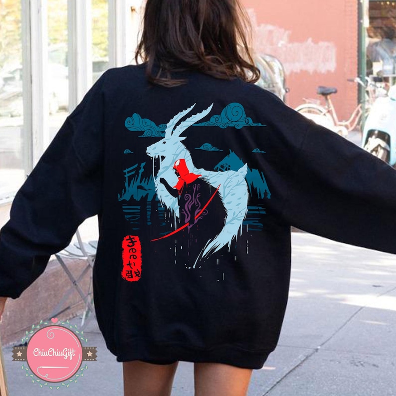 May include: Black sweatshirt featuring a light blue and red illustration of a mythical creature with antlers, a red bow, and Japanese text. The design includes mountains and clouds. The sweatshirt is a casual style.