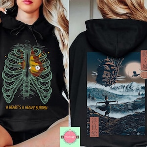 May include: Black hoodie featuring a rib cage design with a heart-shaped graphic and the text "A Heart's a Heavy Burden." The back of the hoodie displays a landscape scene with a castle, a scarecrow, and Japanese text.