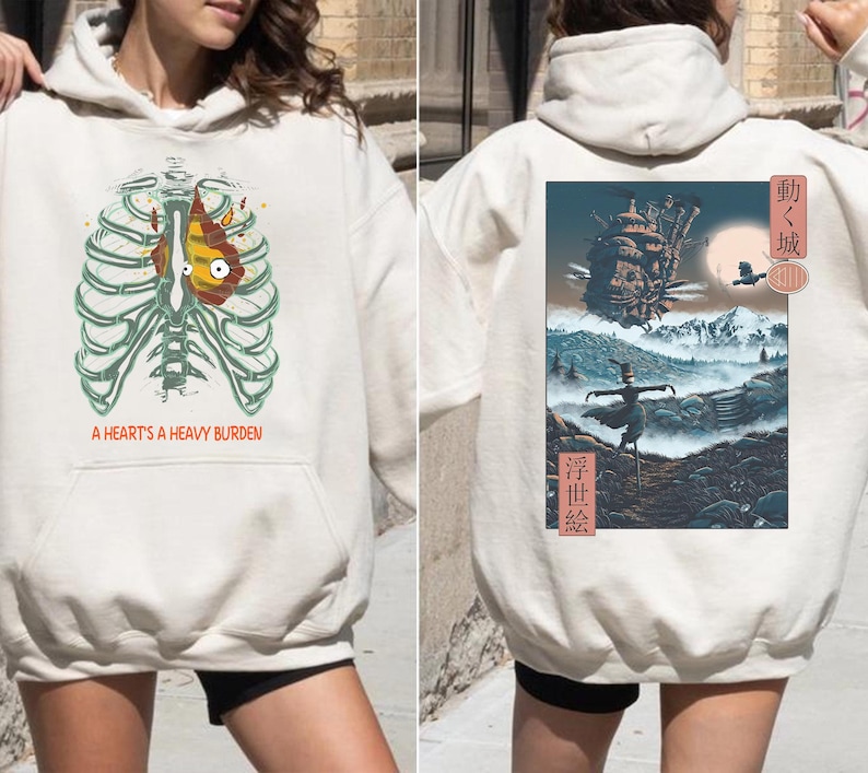 May include: Cream-colored hoodie featuring a graphic of a rib cage with a heart design and the text "A Heart's A Heavy Burden" on the front. The back displays a landscape scene with Japanese text and imagery.