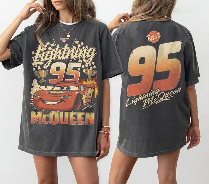 May include: A charcoal gray oversized t-shirt featuring a graphic of the red race car Lightning McQueen with the number 95, checkered flags, and trophies on the front, and a large 95 with the text Lightning McQueen on the back.