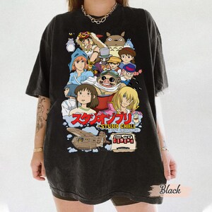 May include: Black t-shirt featuring a Studio Ghibli design with various animated characters. The design includes Japanese text and the words "The Loft Cinema". The shirt is a dark color and has a vintage look.