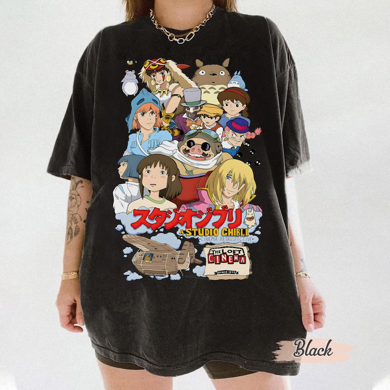 May include: Black t-shirt featuring a Studio Ghibli design with various animated characters. The design includes Japanese text and the words "The Loft Cinema". The shirt is a dark color and has a vintage look.