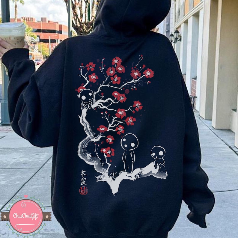 May include: A navy blue hoodie featuring a Japanese-inspired design on the back. The graphic includes a flowering tree with red blossoms and three small, stylized figures. The text in the image is in Japanese.