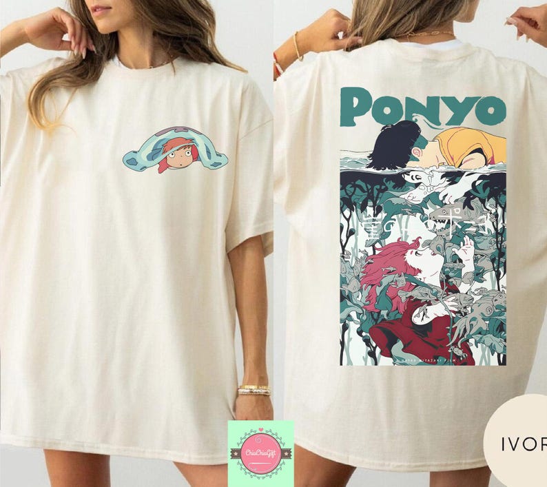 May include: Ivory-colored t-shirt featuring a cartoon graphic of a character under a blue blanket on the front. The back of the shirt displays a colorful illustration with the word "Ponyo" in teal.