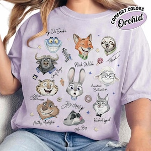 Op de afbeelding: Een lichtpaars T-shirt met stripfiguren uit Zootopia. Het shirt bevat personages als Nick Wilde, Judy Hopps en Flash, met de tekst "COMFORT COLORS Orchid".