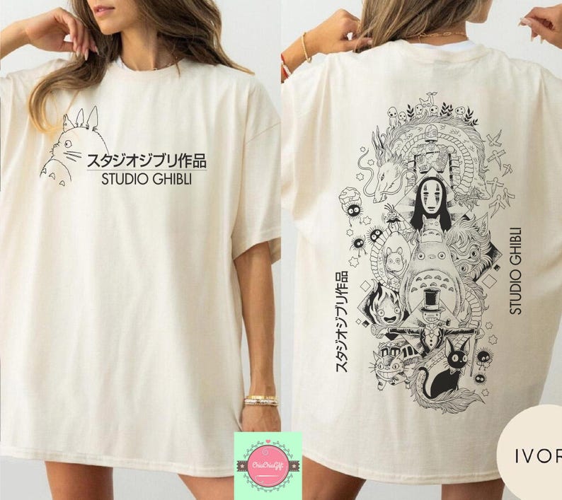 May include: Ivory-colored t-shirt featuring a Studio Ghibli design. The front displays a Totoro graphic with Japanese text and "STUDIO GHIBLI." The back showcases a detailed black and white illustration of various characters and the text "STUDIO GHIBLI."