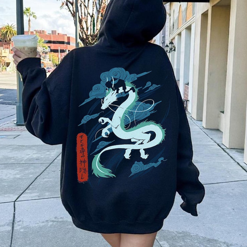 May include: Black hoodie featuring a white and teal dragon design with cloud accents. The dragon is the focal point, with Japanese text on the lower left. The hoodie has a drawstring hood and long sleeves.