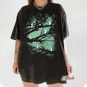 May include: Black oversized t-shirt featuring a tree design with white spirit figures. The graphic has a teal and yellow background. The shirt has short sleeves and a relaxed fit. The word "Black" is printed on the bottom right.