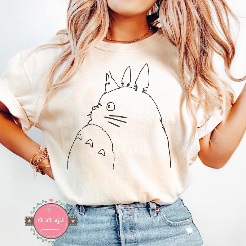 Puede incluir: Camiseta color crema con un dibujo lineal negro del personaje Totoro de la pel&iacute;cula de animaci&oacute;n Mi vecino Totoro. El dise&ntilde;o est&aacute; centrado en la parte delantera de la camiseta. La camiseta se combina con unos vaqueros azules.