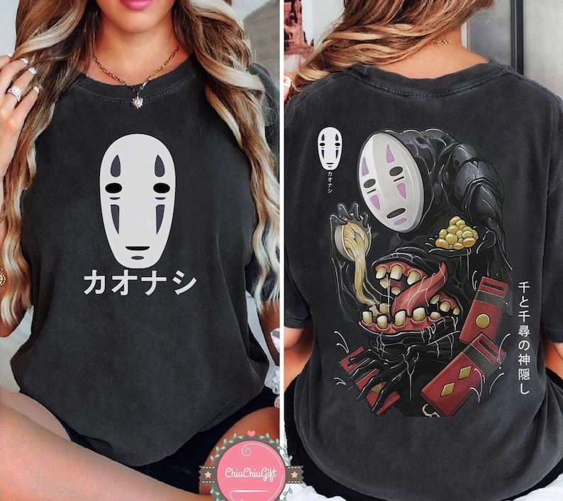 May include: Dark gray t-shirt featuring a white No-Face mask design with Japanese text "Kaonashi" on the front. The back of the shirt displays a detailed illustration of No-Face with Japanese text. A unique graphic tee.
