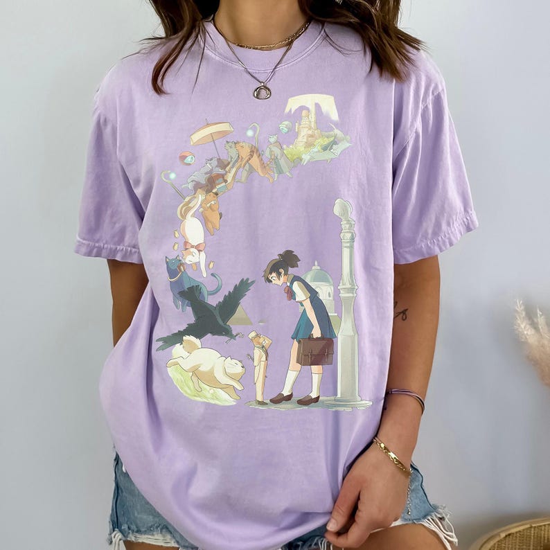 Puede incluir: Camiseta de color lila claro con una ilustraci&oacute;n de estilo anime. El dise&ntilde;o muestra a una colegiala rodeada de personajes de animales y un paisaje urbano flotante. La camiseta tiene mangas cortas y un corte holgado.