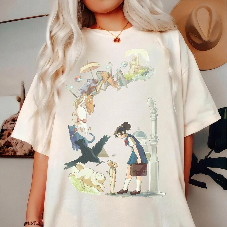 Puede incluir: Camiseta color crema con una ilustraci&oacute;n caprichosa de estilo anime. El dise&ntilde;o incluye una ni&ntilde;a con uniforme escolar, gatos, un cuervo y un paisaje urbano. La obra de arte est&aacute; detallada con colores suaves y una calidad on&iacute;rica.