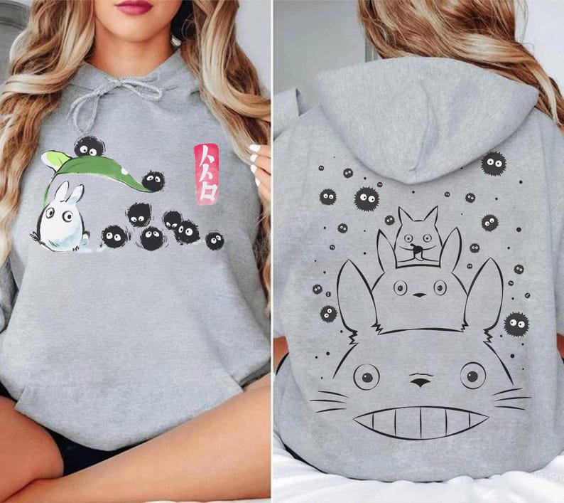 May include: Gray hoodie featuring a front graphic of a white rabbit-like creature with black soot sprites and a green leaf. The back of the hoodie displays a large graphic of the same creature with two smaller ones. The Japanese text is visible.