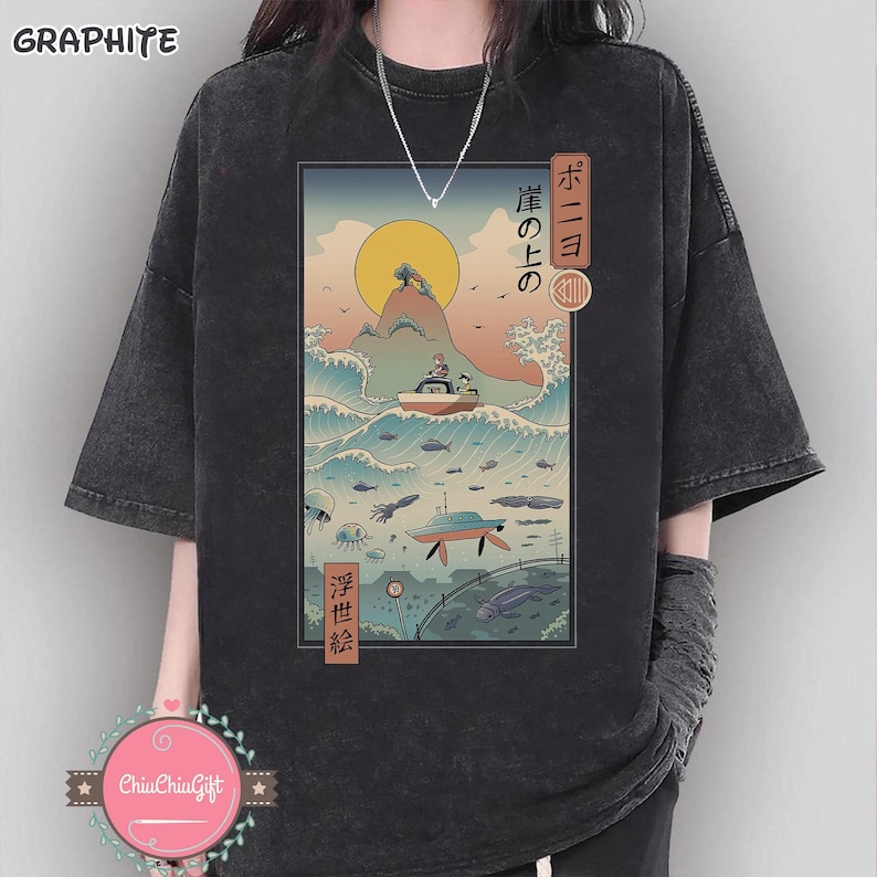 May include: Dark gray t-shirt featuring a Japanese-inspired illustration of a boat on waves, a rising sun, and marine life. The graphic includes Japanese text and a retro aesthetic. The shirt has short sleeves and a relaxed fit.