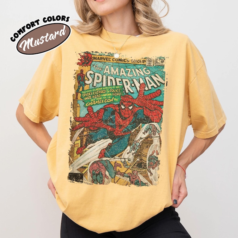 K&ouml;nnte beinhalten: Ein senfgelbes Kurzarm-T-Shirt mit einem Vintage-Marvel-Comic-Cover-Aufdruck von The Amazing Spider-Man. Der Druck zeigt Spider-Man in seinem rot-blauen Anzug mit dem Text The Amazing Spider-Man sowie dem Schriftzug Comfort Colors.