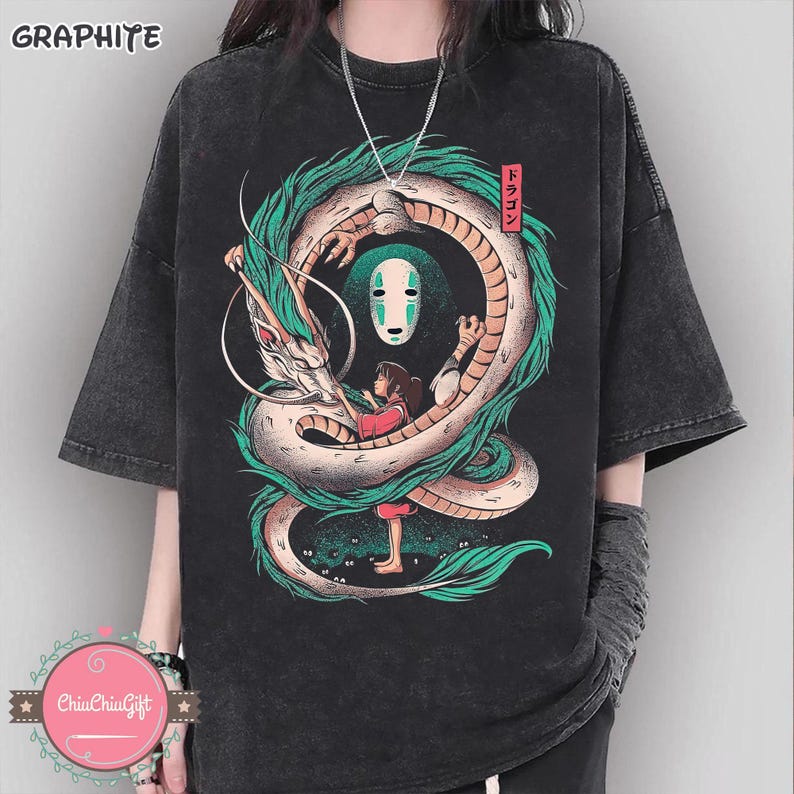 May include: Dark gray t-shirt featuring a colorful graphic of a dragon, a girl, and a white mask. The dragon is green and white, and the girl is wearing a red shirt. The word "GRAPHITE" is at the top left. The Japanese word "Dragon" is on the right.