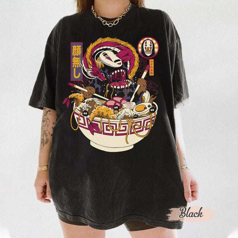 K&ouml;nnte beinhalten: Schwarzes Grafik-T-Shirt mit einer farbenfrohen Illustration einer Ramen-Sch&uuml;ssel, japanischen Schriftzeichen und einer drachenartigen Kreatur. Das Design umfasst Nudeln, Eier und andere Ramen-Zutaten. Das Shirt hat eine Vintage-Waschung.
