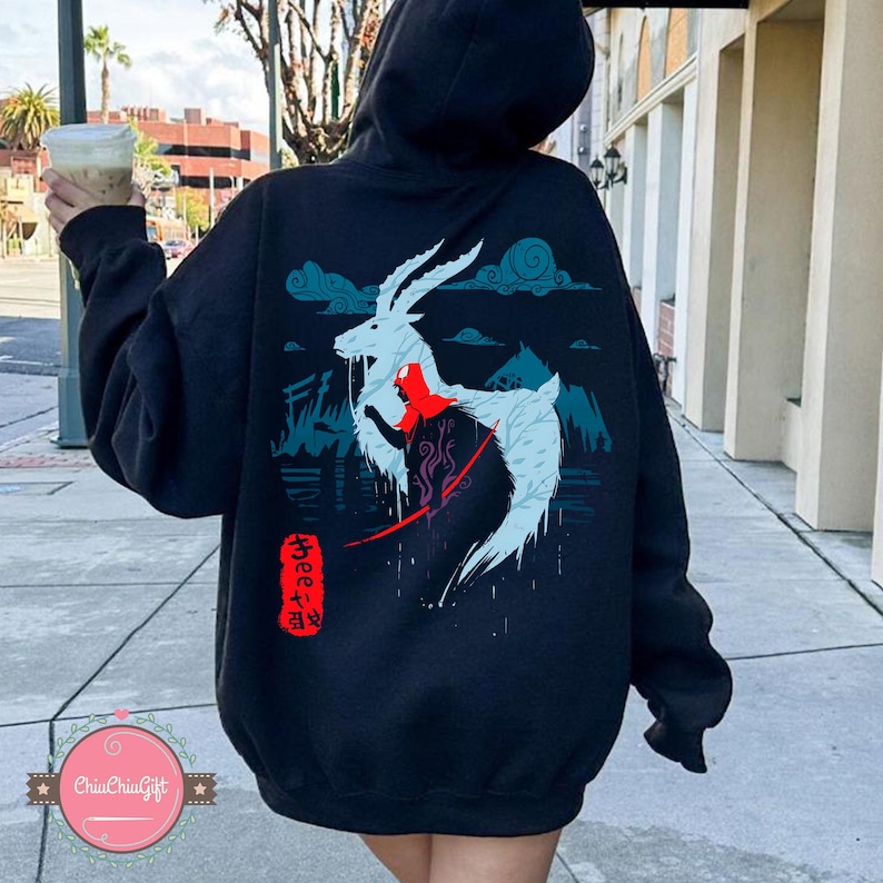 May include: Black hoodie featuring a white and blue illustration of a deer-like creature with red accents, set against a mountain and cloud backdrop. Japanese text is visible on the lower right. The hoodie has a drawstring hood.