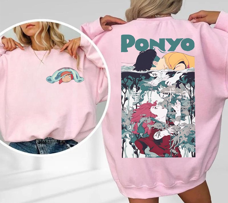 May include: Pink sweatshirt featuring a colorful graphic from the animated film "Ponyo." The front has a small cartoon image, while the back displays a larger illustration with the film's title in teal letters. The design includes characters and aquatic elements.