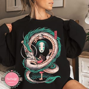 May include: Black sweatshirt featuring a detailed illustration of a dragon, a girl, and a character from Spirited Away. The dragon is white and green, with the girl in a red outfit. The Japanese word "Dragon" is in a red box.