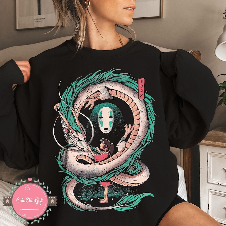 May include: Black sweatshirt featuring a detailed illustration of a dragon, a girl, and a character from Spirited Away. The dragon is white and green, with the girl in a red outfit. The Japanese word "Dragon" is in a red box.