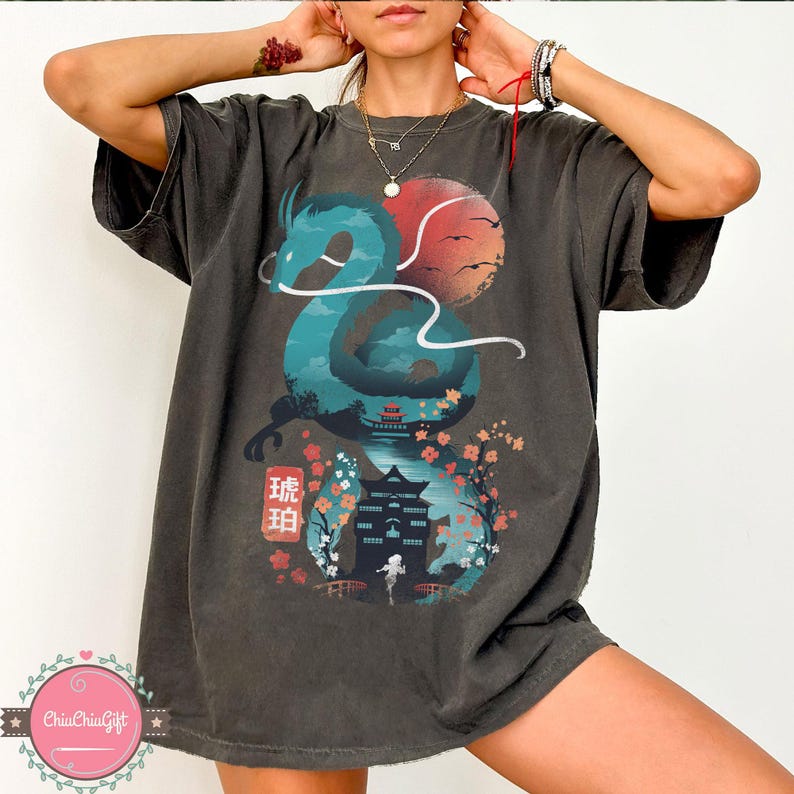 Puede incluir: Camiseta gris oscuro con un dise&ntilde;o de drag&oacute;n turquesa, un sol rojo y naranja, un templo japon&eacute;s y flores de cerezo. La camiseta incluye texto japon&eacute;s y tiene un corte holgado y c&oacute;modo.