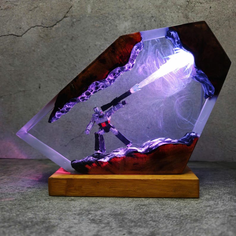 May include: A unique resin lamp featuring a robot figure with a weapon, emitting a bright light. The lamp is encased in a clear resin with a wooden base and accents. The design incorporates red and purple hues, creating a striking visual effect.