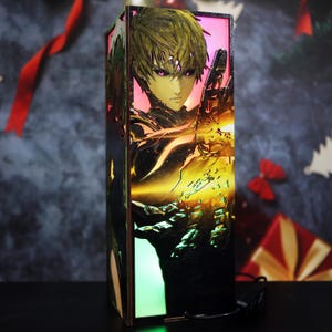 Könnte beinhalten: Rechteckige, beleuchtete Holzbox mit einer detaillierten Anime-Charakter-Illustration. Das Kunstwerk zeigt eine Figur mit stacheligen blonden Haaren und intensiven violetten Augen, vor einem leuchtenden Hintergrund. Die Box strahlt ein warmes, farbenfrohes Licht aus.